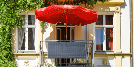 Balkonkraftwerk an Altbauhaus mit Balkon und rotem Sonnenschirm